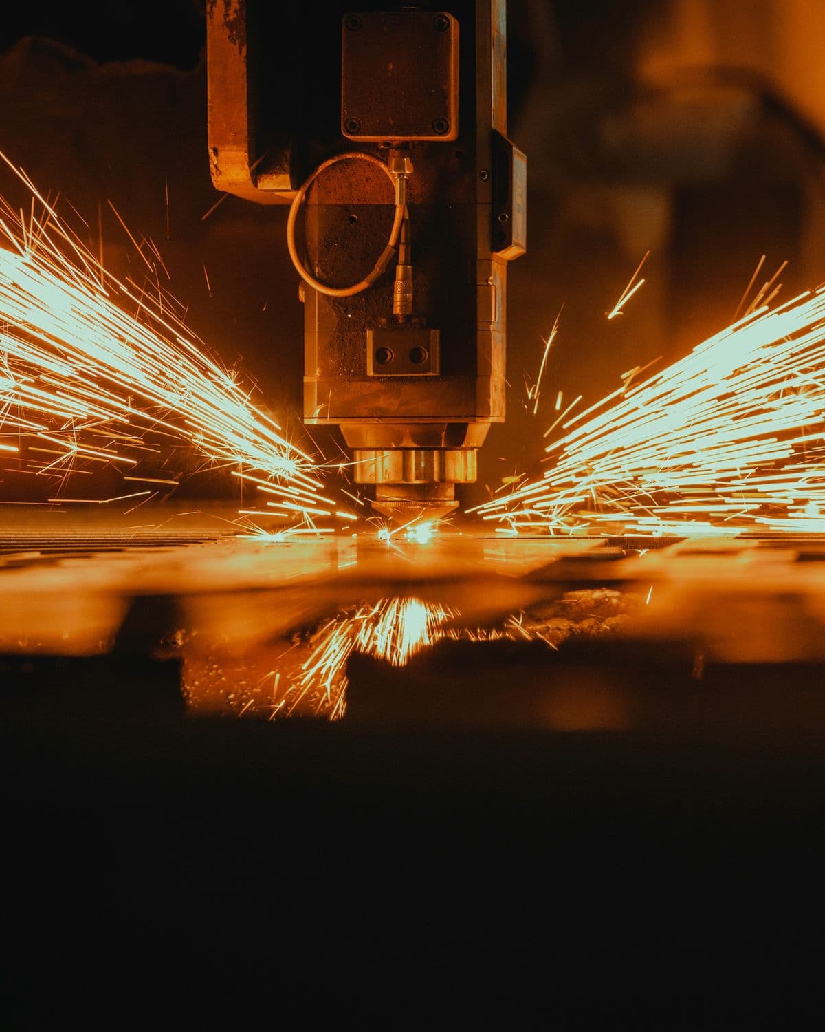 Laser cutter throwing sparks across a steel plate