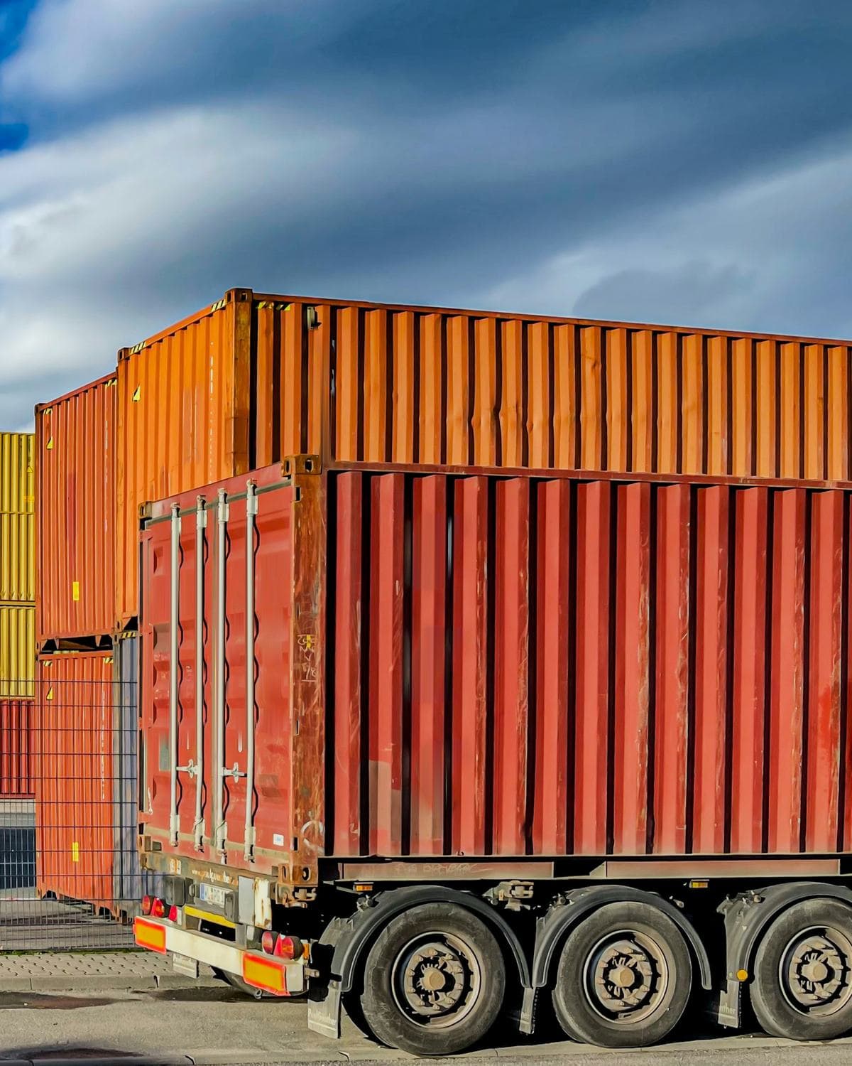 Stacked shipping containers and a truck under a blue sky